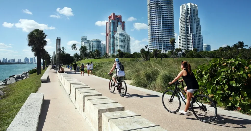 Young couple riding bikes on Miami Beach biking trails near the ocean in Florida for cyclists looking for bike paths